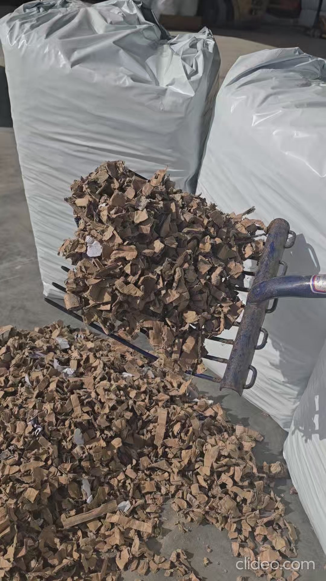 Video showing shredded cardboard pet bedding falling from a mucking out fork to demonstrate texture and flow